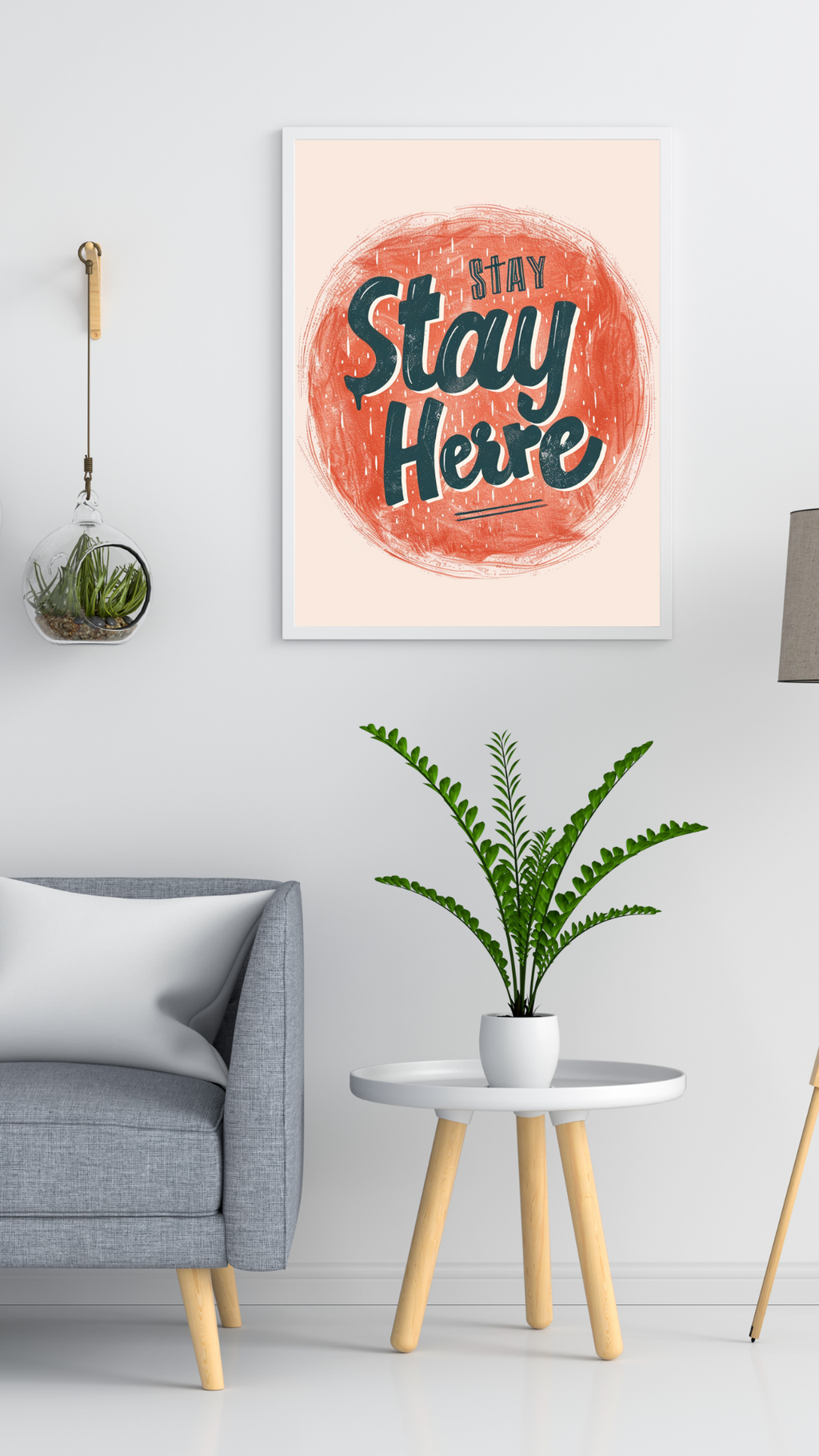 Grått minimalistiskt typografiposter med texten "Stay Here" i Nordanio-design, inramad och hängande på vägg.