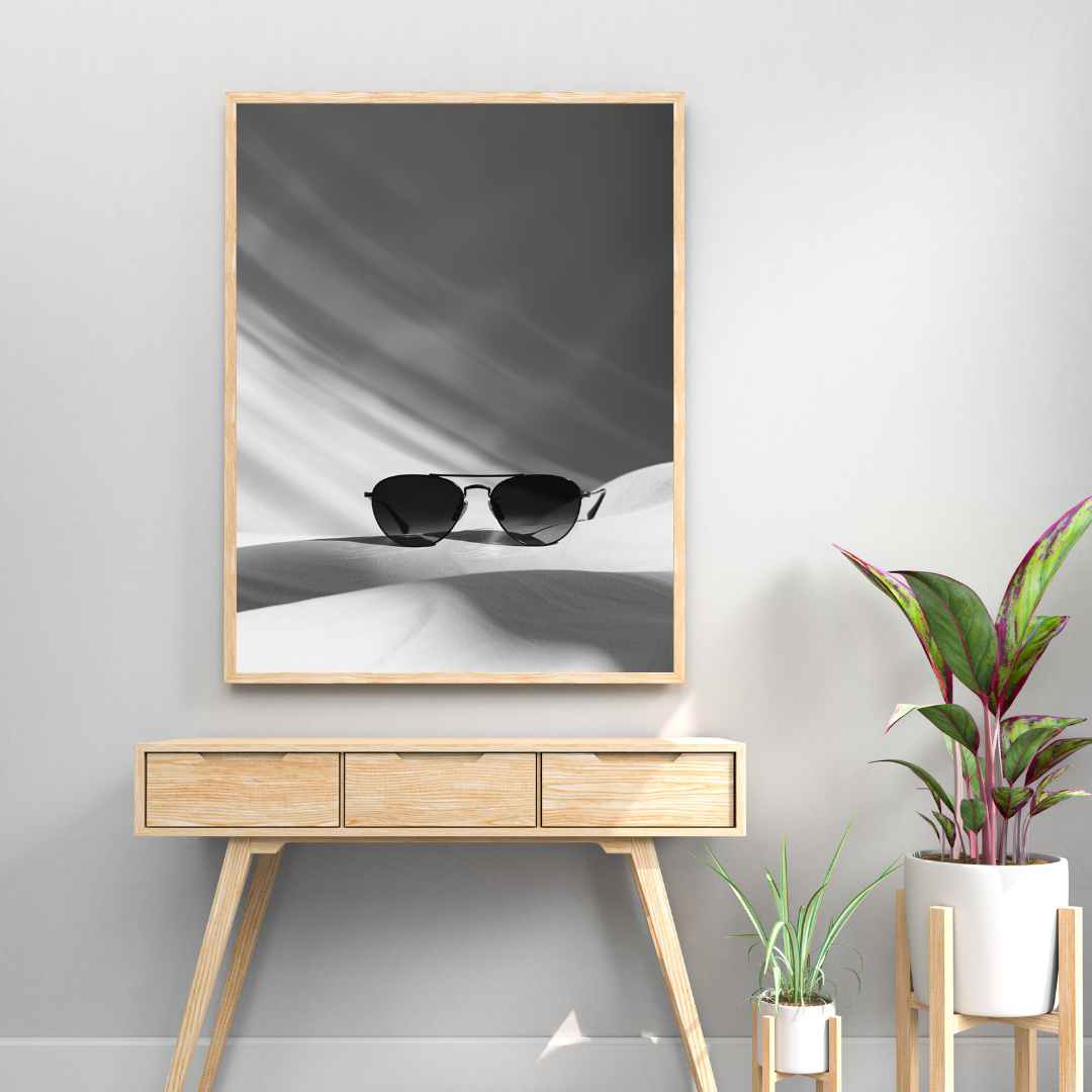 Svartvit postersbild av Nordanio med solglasögonmotiv, inramad och upphängd på en ljusgrå väggram.